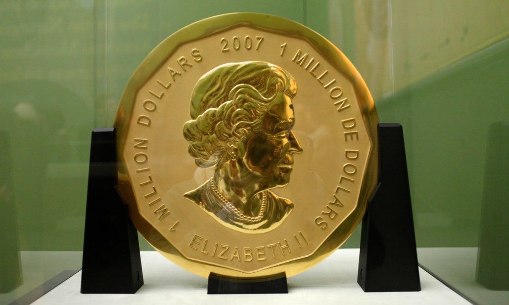 A large, gold-plated coin, dazzling in its splendor, features a profile portrait of a person adorned with pearls. Engraved text around this exquisite piece reads "1 MILLION DOLLARS 2007 1 MILLION DE DOLLARS" and "ELIZABETH II". The COINS collection centerpiece is displayed upright on a black stand.